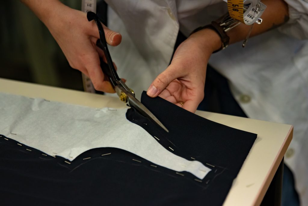 Tailor cutting fabric with scissors