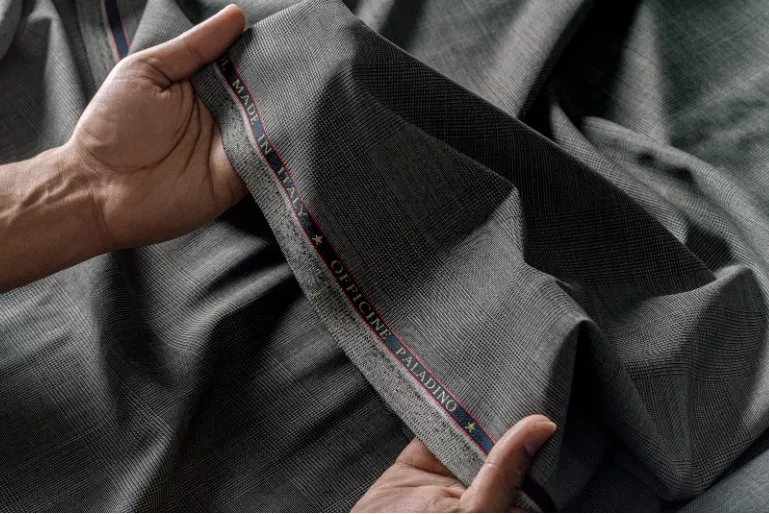 Hands holding up a roll of wool fabric