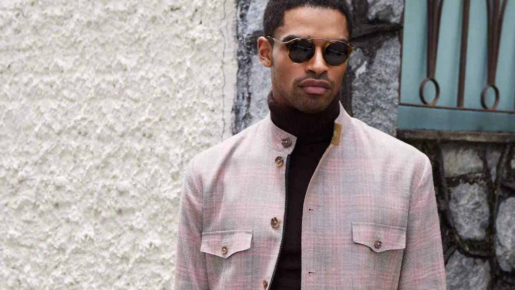 A model wears OP2221 Tokyo Pink, a wool, silk, and linen blend fabric in grey glen plaid with orange overcheck from Officine Paladino.